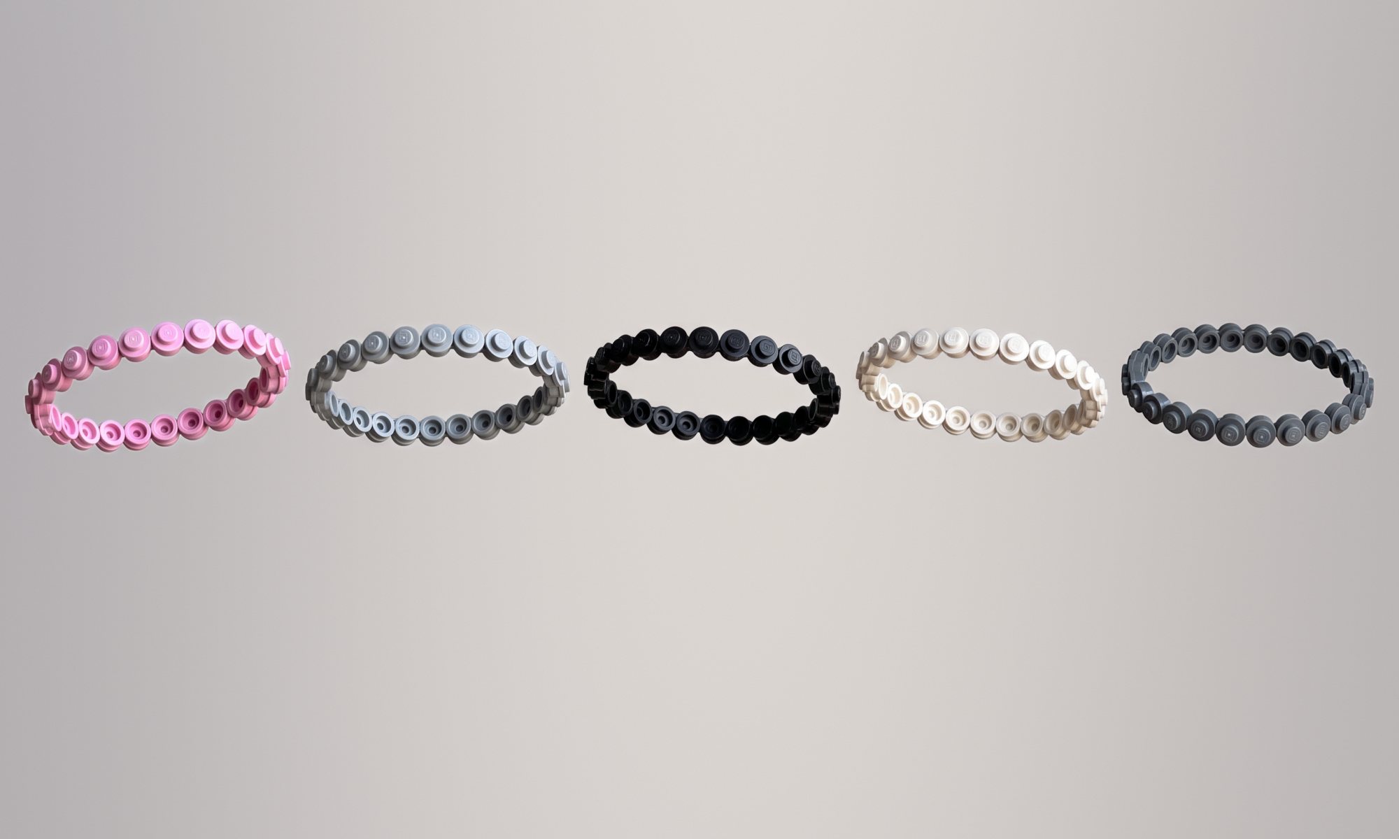 Five Base Brick Bracelets floating: pink, light grey, black, white and dark grey